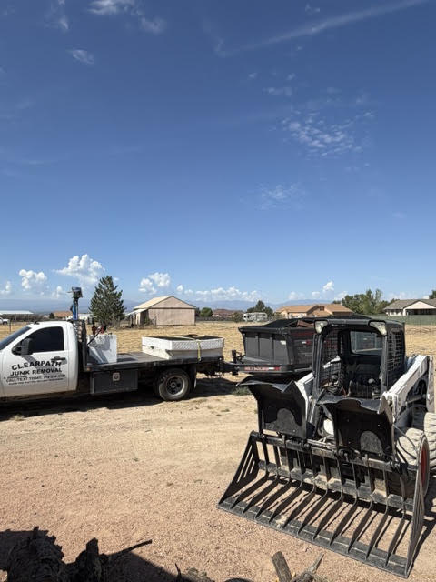 ClearPath dump trailer and Bobcat skid steer during an acre-lot property cleanout near Pueblo