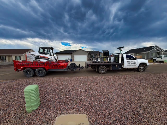 ClearPath Junk Removal flatbed truck and loaded skid steer on a dump trailer in a Pueblo West neighborhood